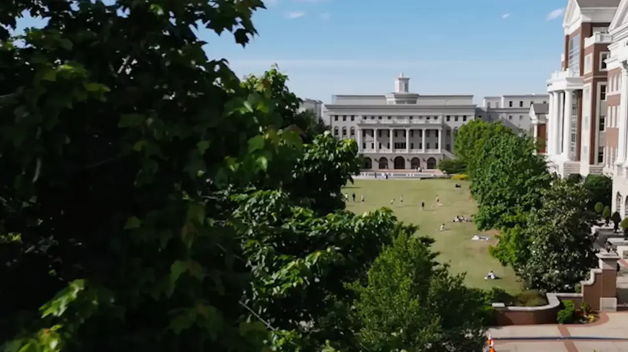 View of Belmont University’s central lawn and academic buildings framed by trees on a sunny day.