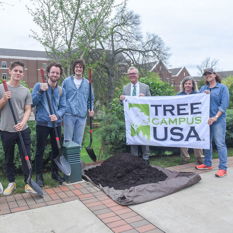 Students and Staff member holding a Tree Campus USA sign