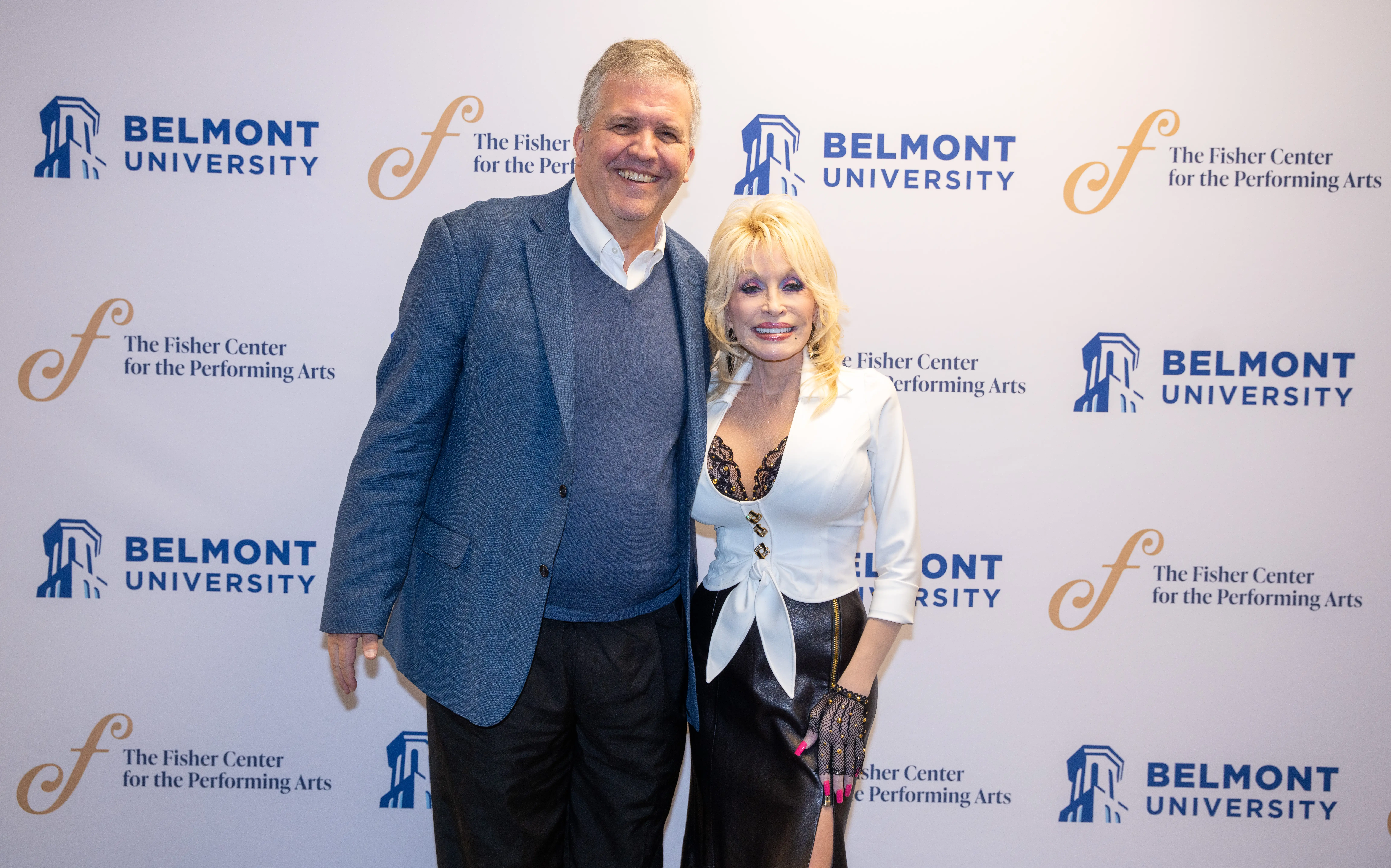 Belmont University President Dr. Greg Jones poses with Dolly Parton in front of a step-and-repeat banner for Belmont and The Fisher Center for the Performing Arts.