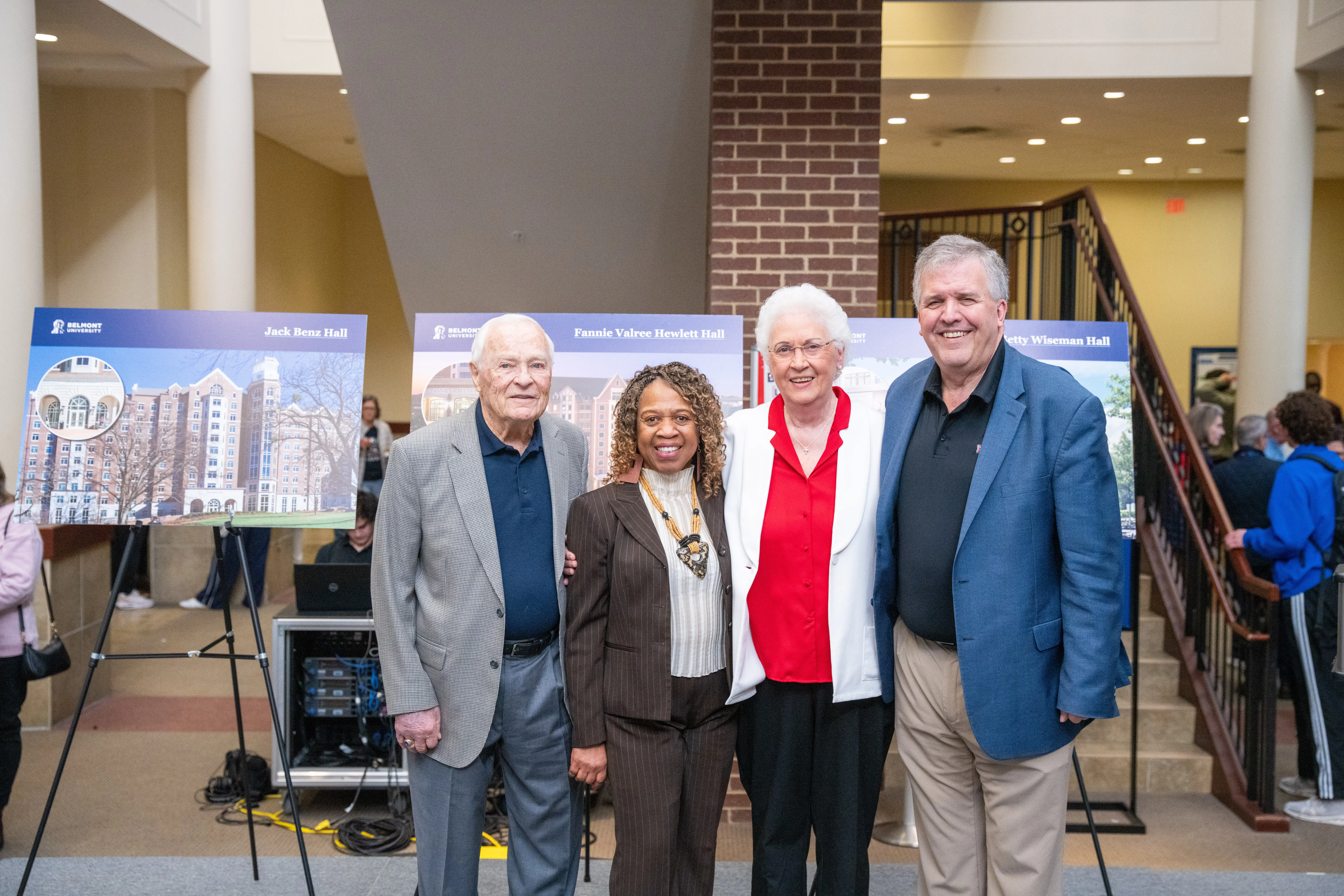 Jack Benz, Fannie Hewlett, Betty Wiseman, and Belmont President Dr. Greg Jones stand smiling in front of posters announcing new residence halls named in their honor.