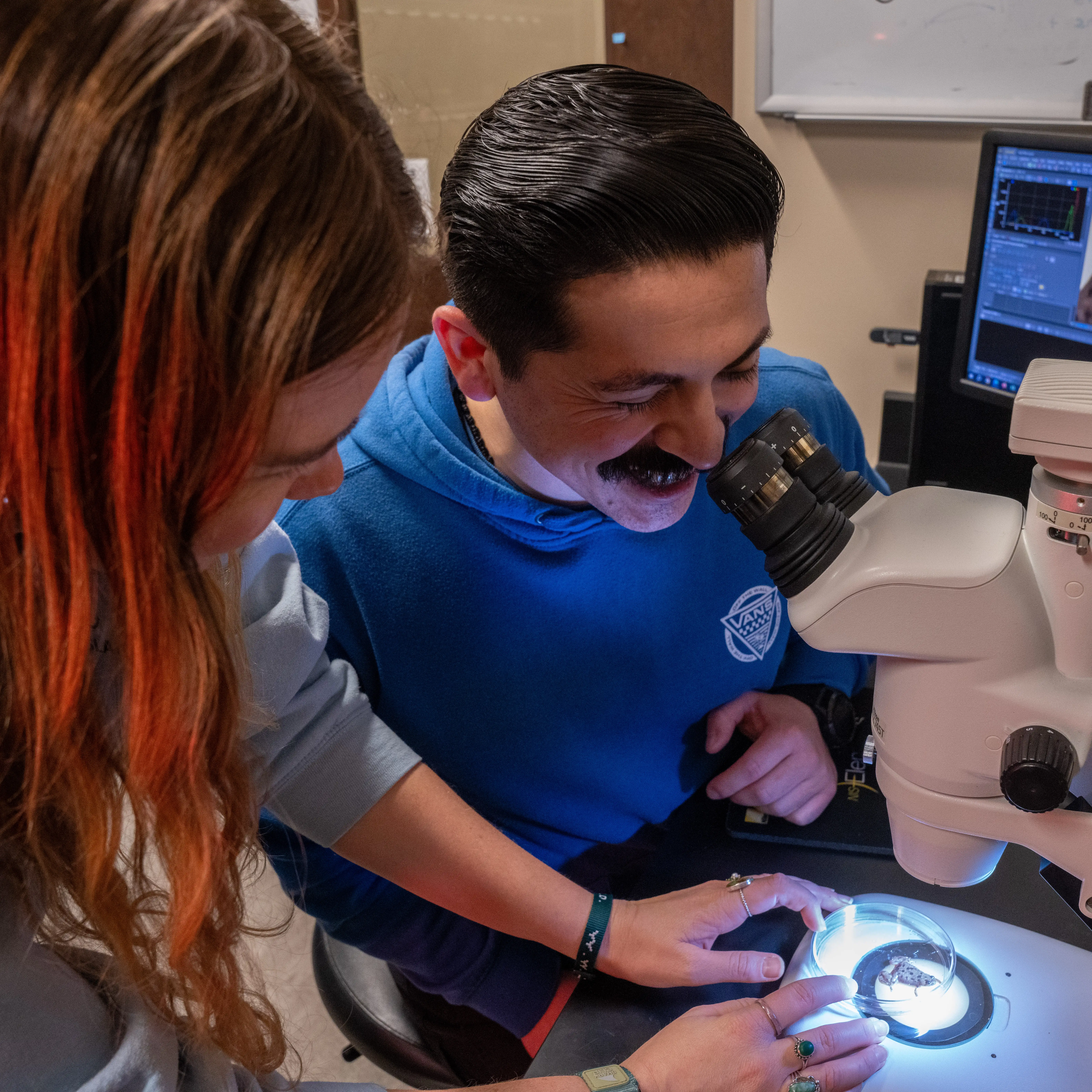 Belmont University students examine a specimen under a microscope in a science lab.