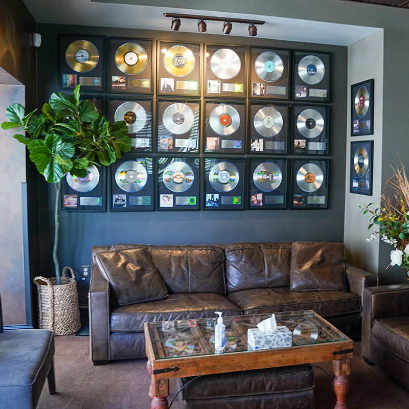 The seating area of OceanWay Studios. A couch sits in front of a wall of framed records.