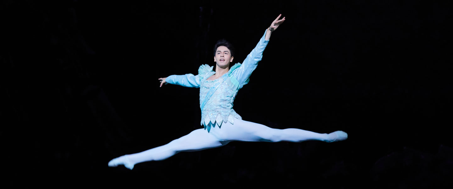 A dancer leaps through the air while on stage.