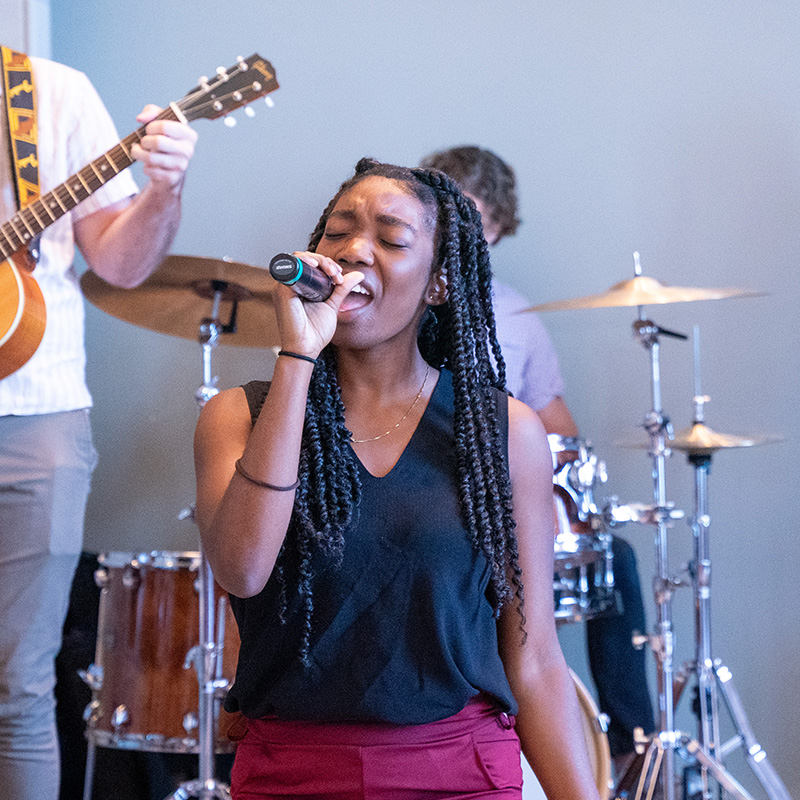 A female student sings with a worship band.