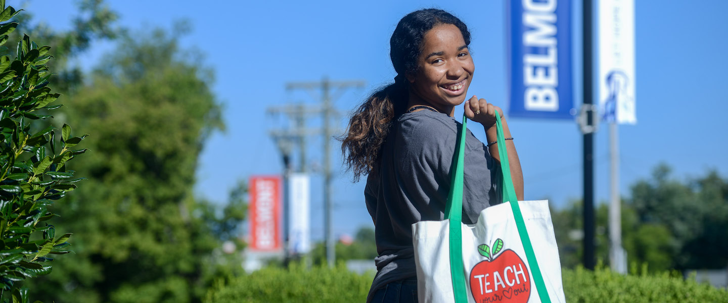 student smiles with a teach tote on her shoulder
