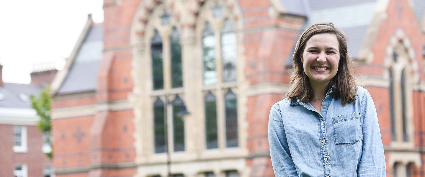 A female student stands smiling outside of an old church in Belfast, Ireland.