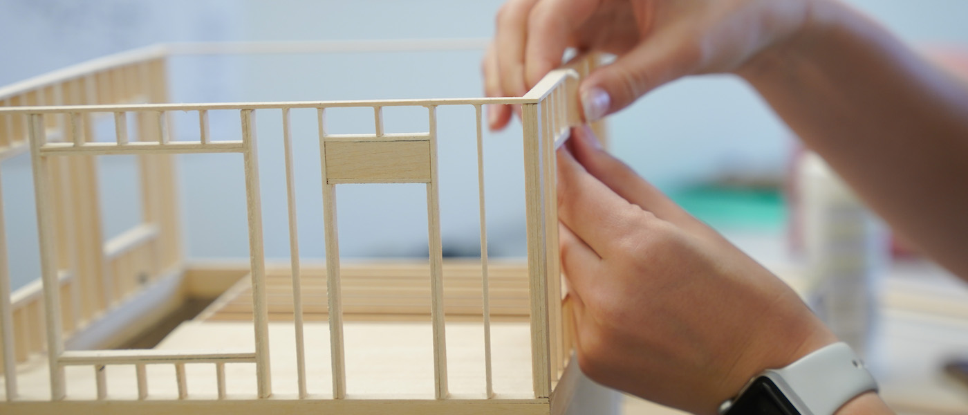 a model building with student hands pictured. 