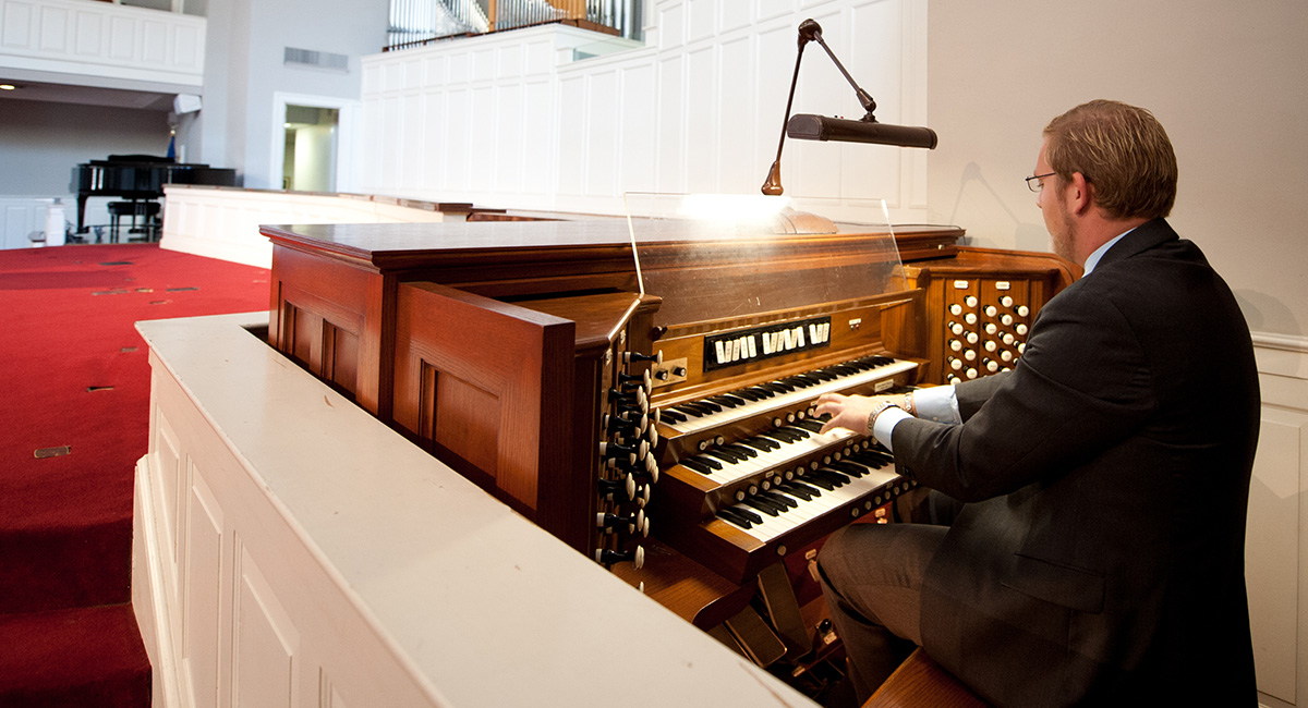 A man sits at a church organ and plays.