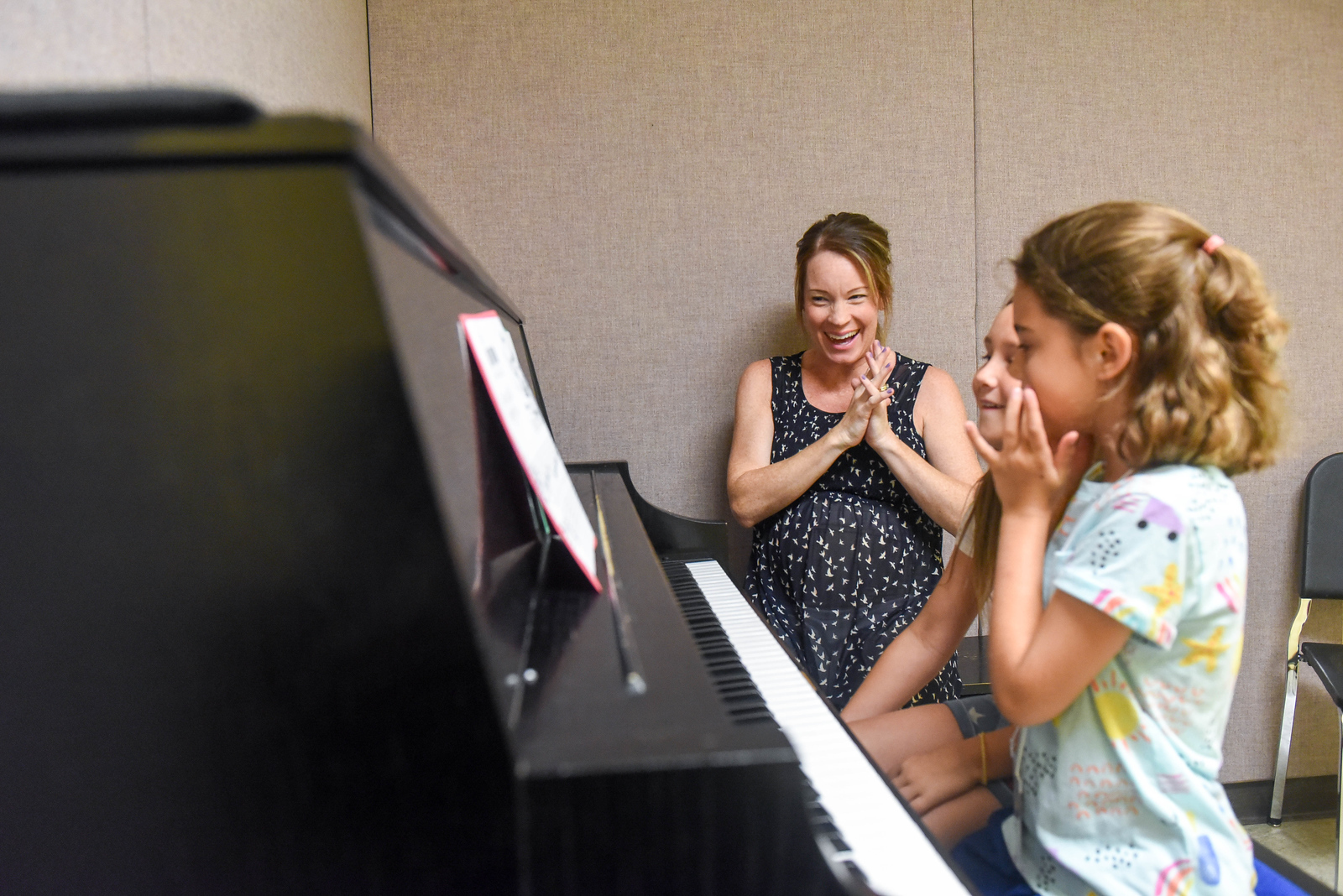woman giving a piano lesson to two girls