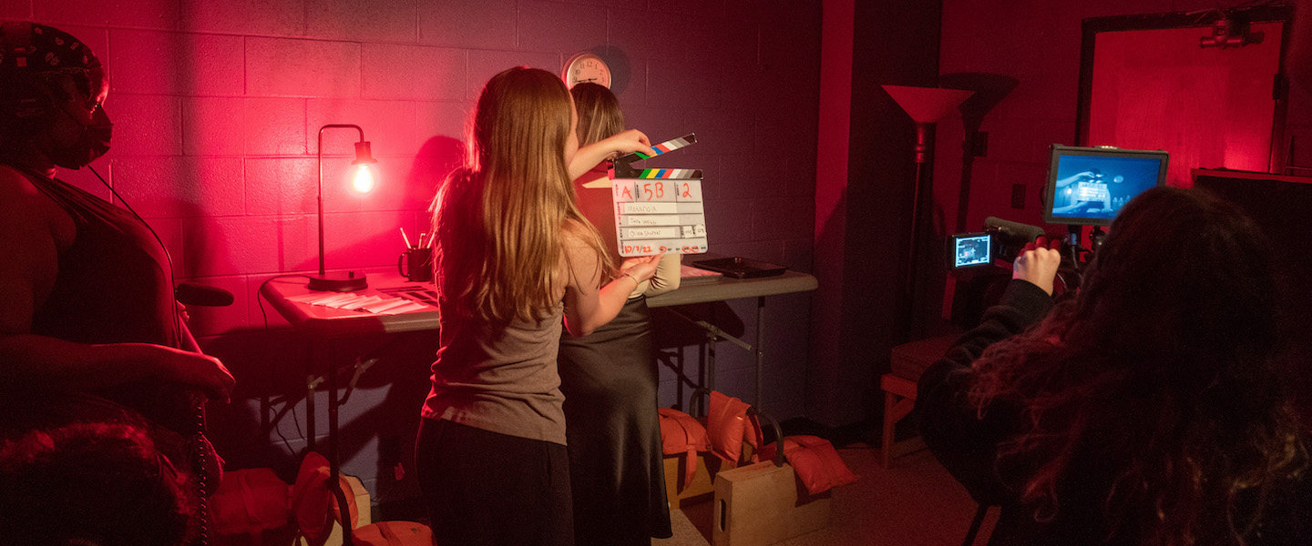 Female student preps slate board as filming begins