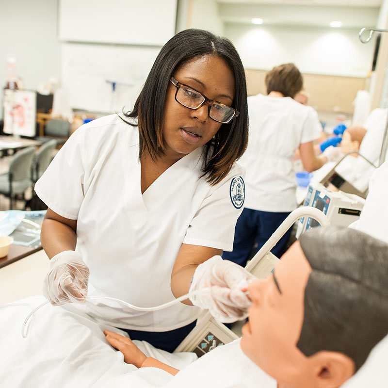 Two nursing students working with a patient simulator
