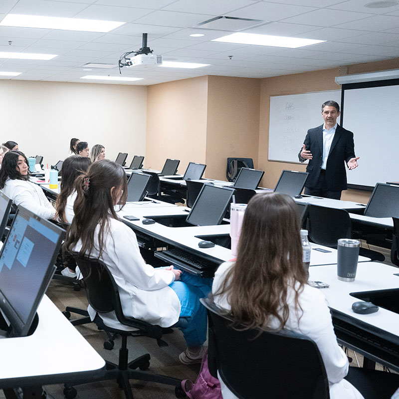Pharmacy Students listening to a business professor in a computer lab