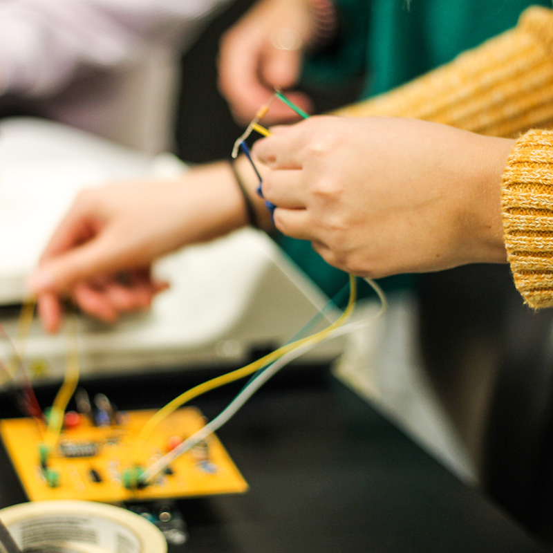 A close-up image of a student's hands working with wires.