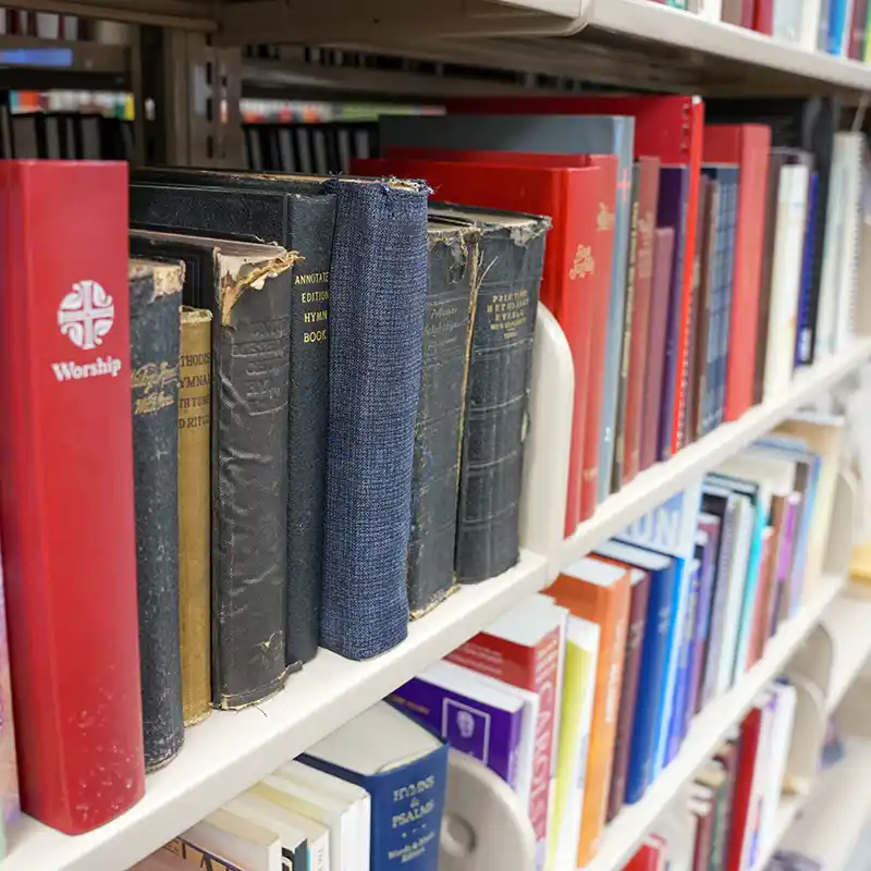 Shelf of hymnals and publishing books in the library.