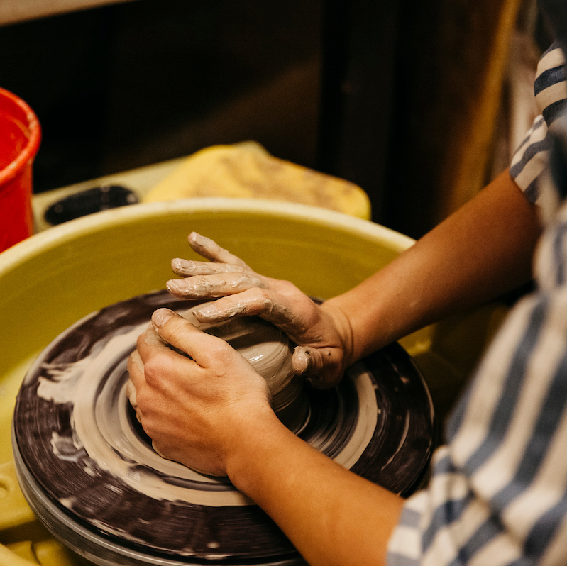 Close up of student turning clay on a pottery wheel