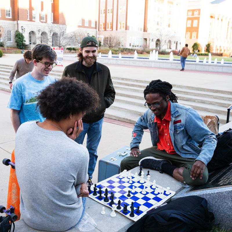 a diverse group of male belmont students playing chess on campus