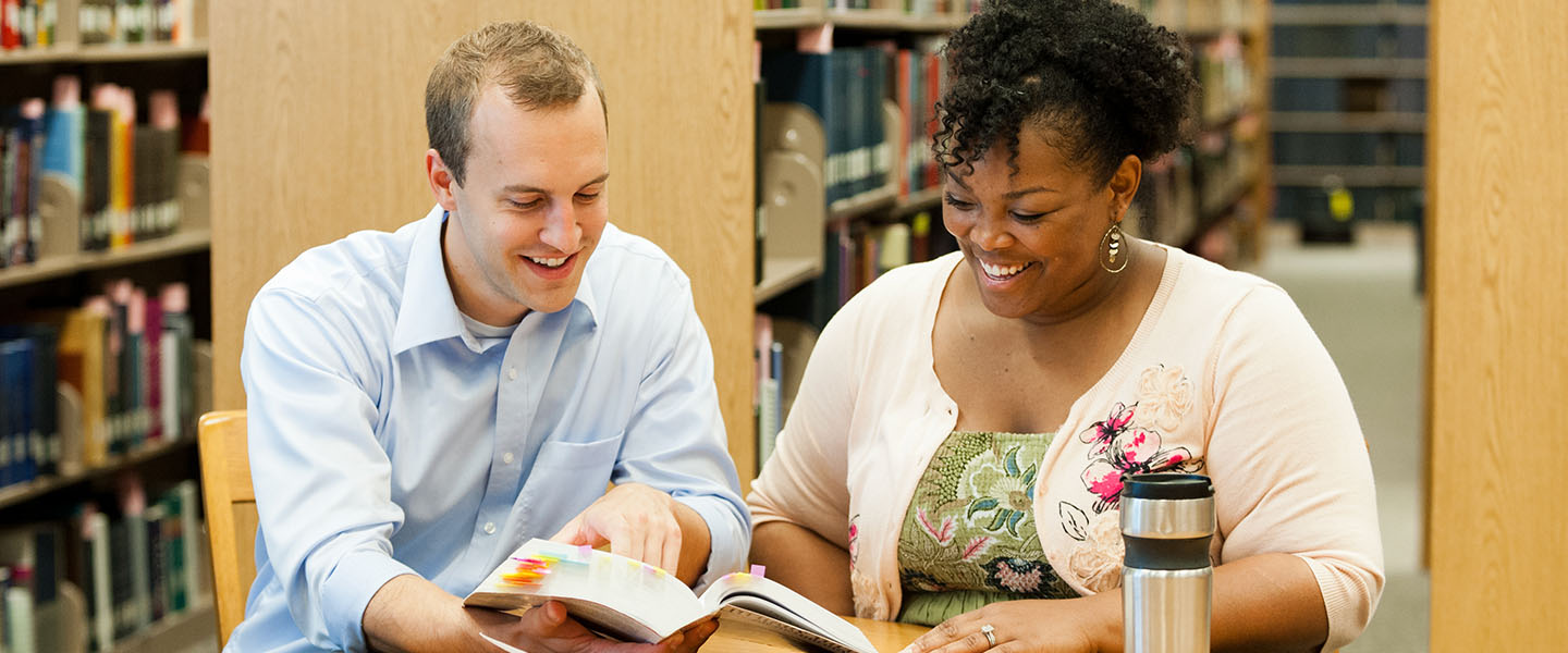 Two graduate students working in the library together