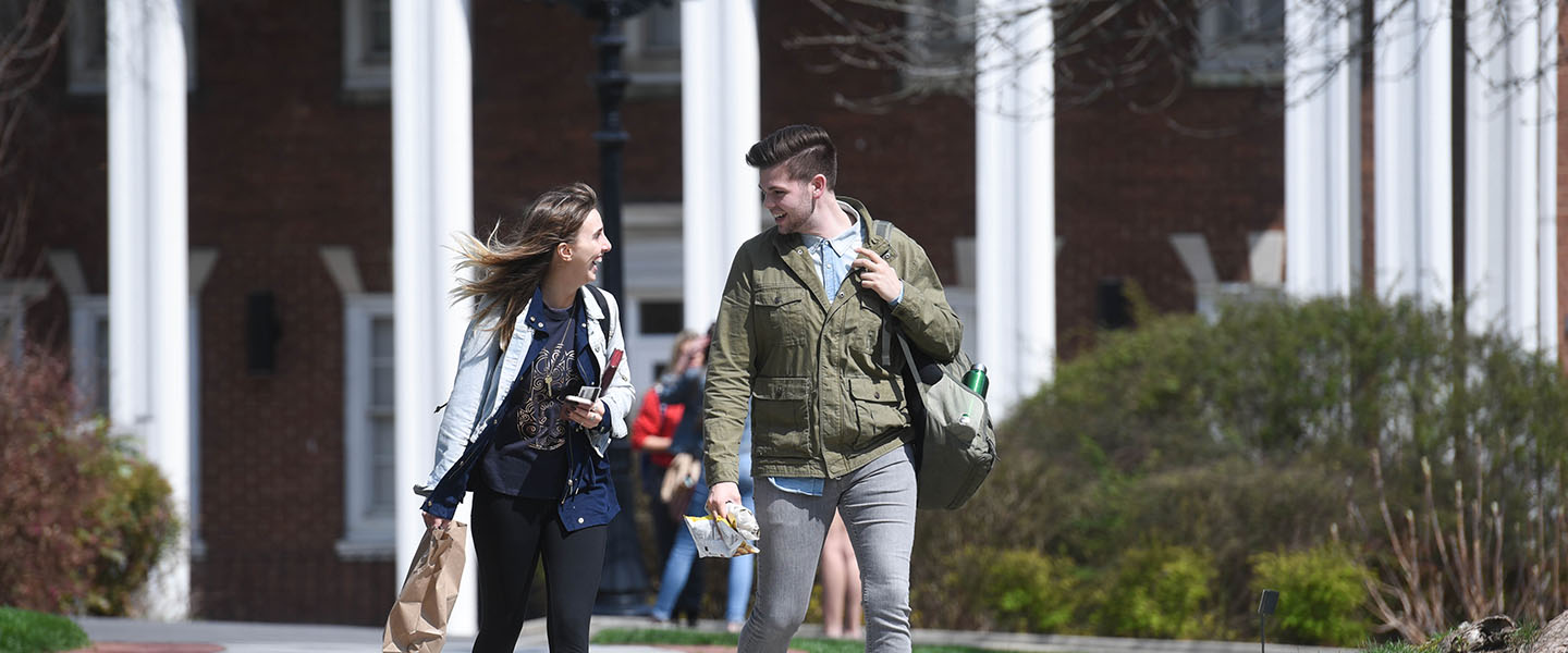 A male and female student walking across campus in the spring
