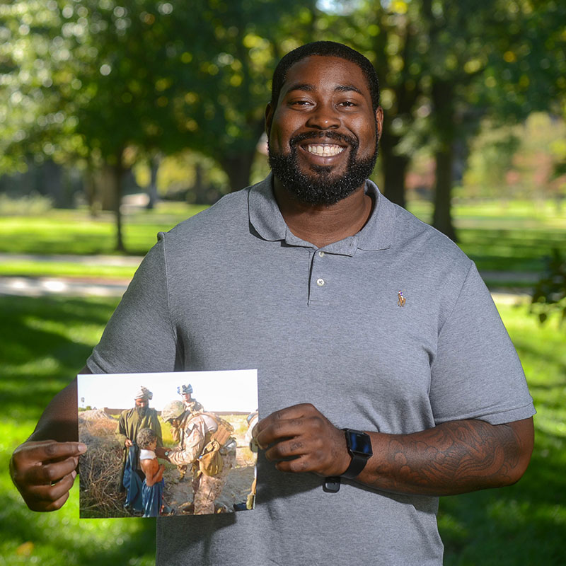 A male Veteran holds a photo of when he served
