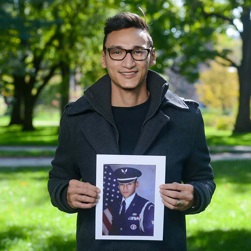 A male veteran holding a photo of himself when he served