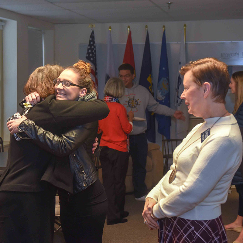 Members of our Veterans Success team hugging a Veteran at an event