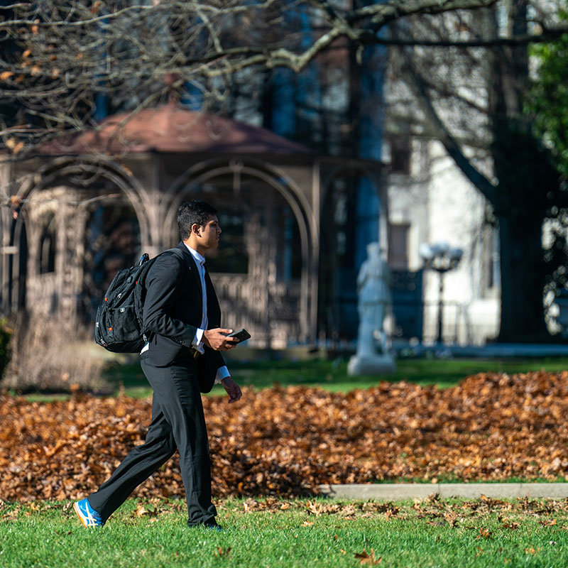A male student walks across campus in the fall