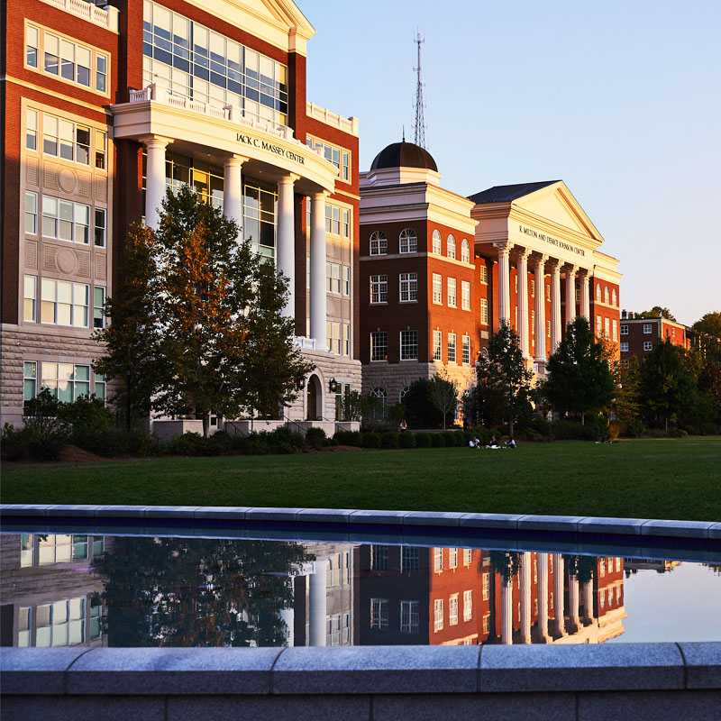 An image of the Jack C. Massey Building reflected in the fountain pool on a fall day