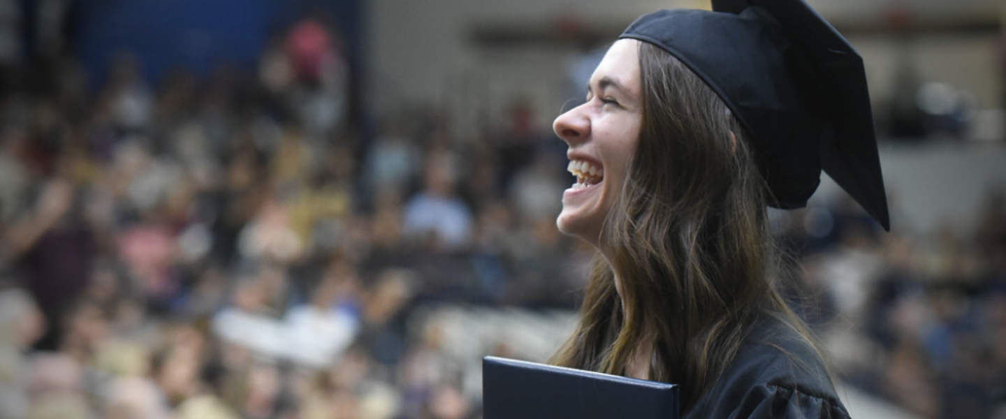 A female graduate smiles during her graduation ceremony.