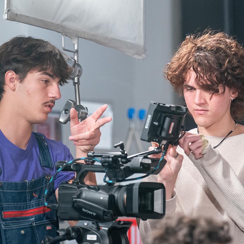 Two students setting up camera during film class
