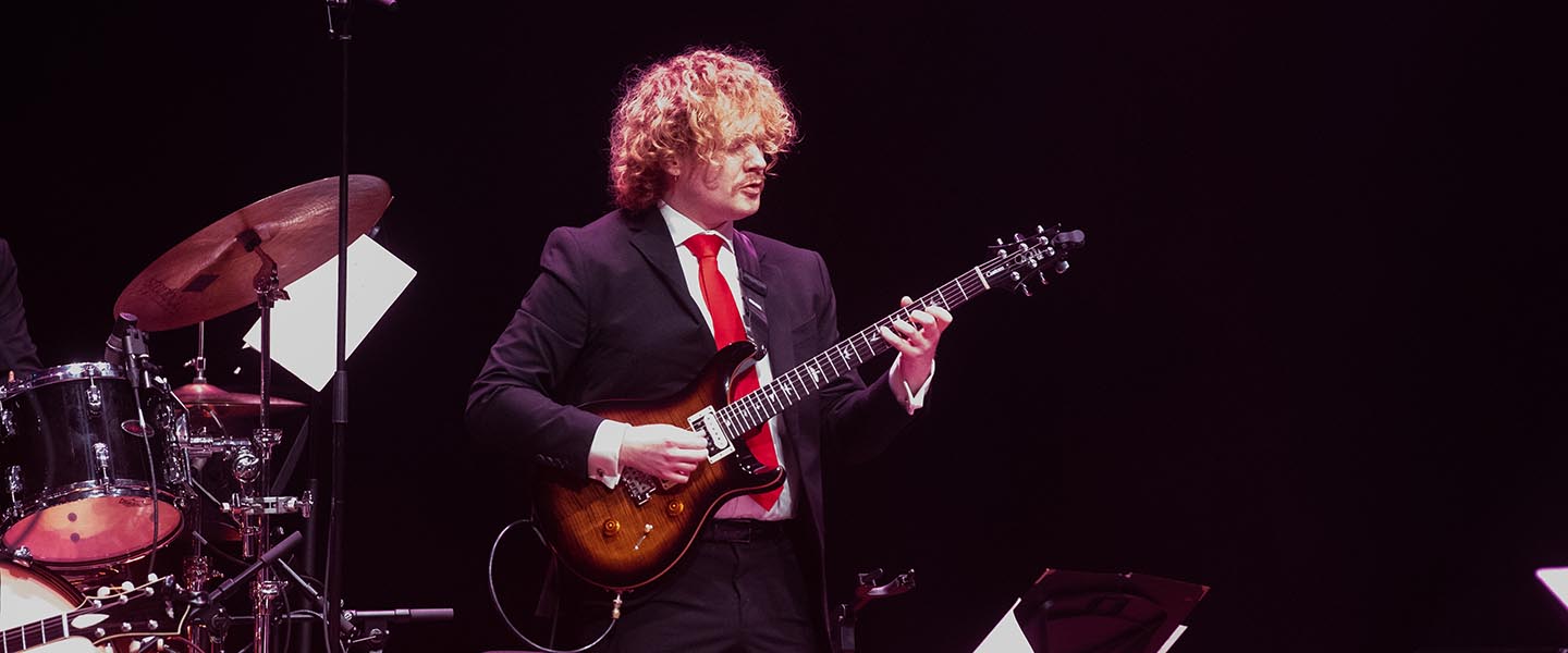 Student plays guitar on stage to celebrate a night of jazz at Belmont University