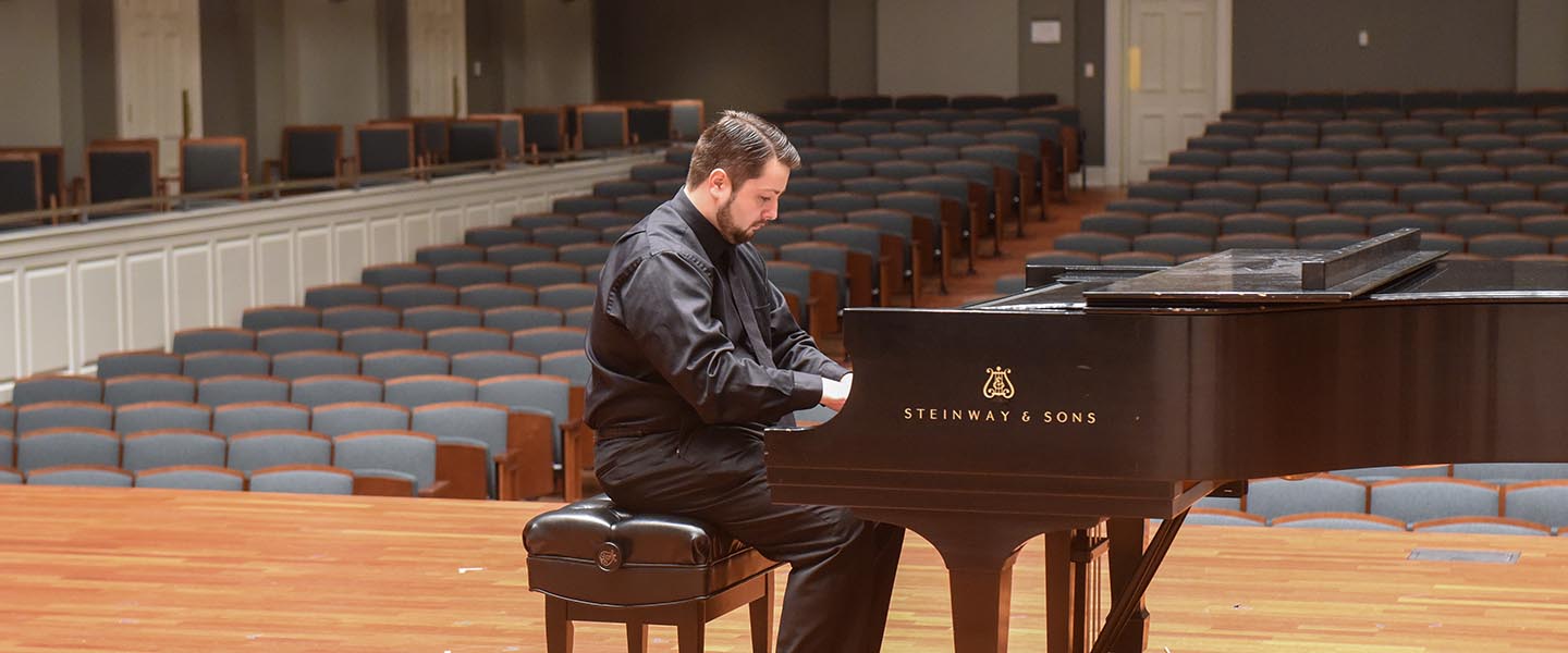 Graduate student plays piano on stage
