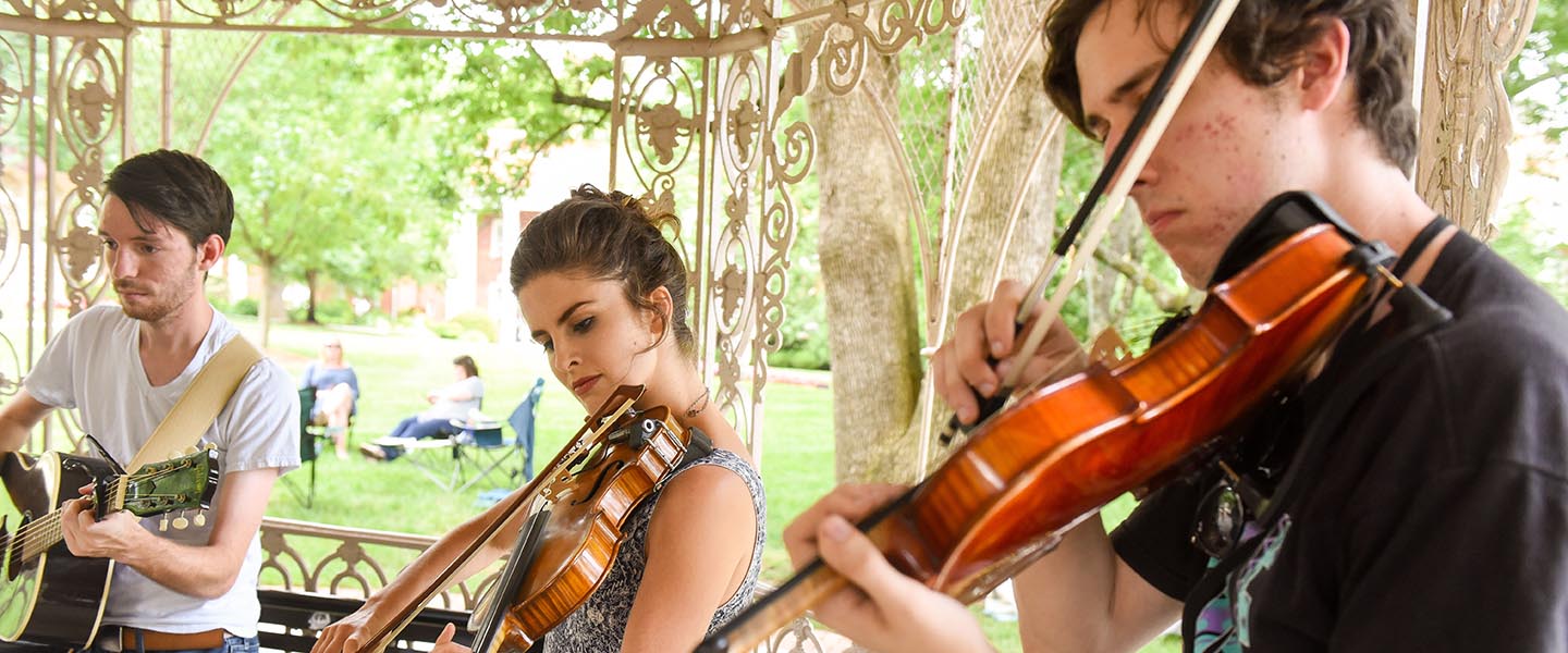 Students playing instruments in gazebo on historic side of campus