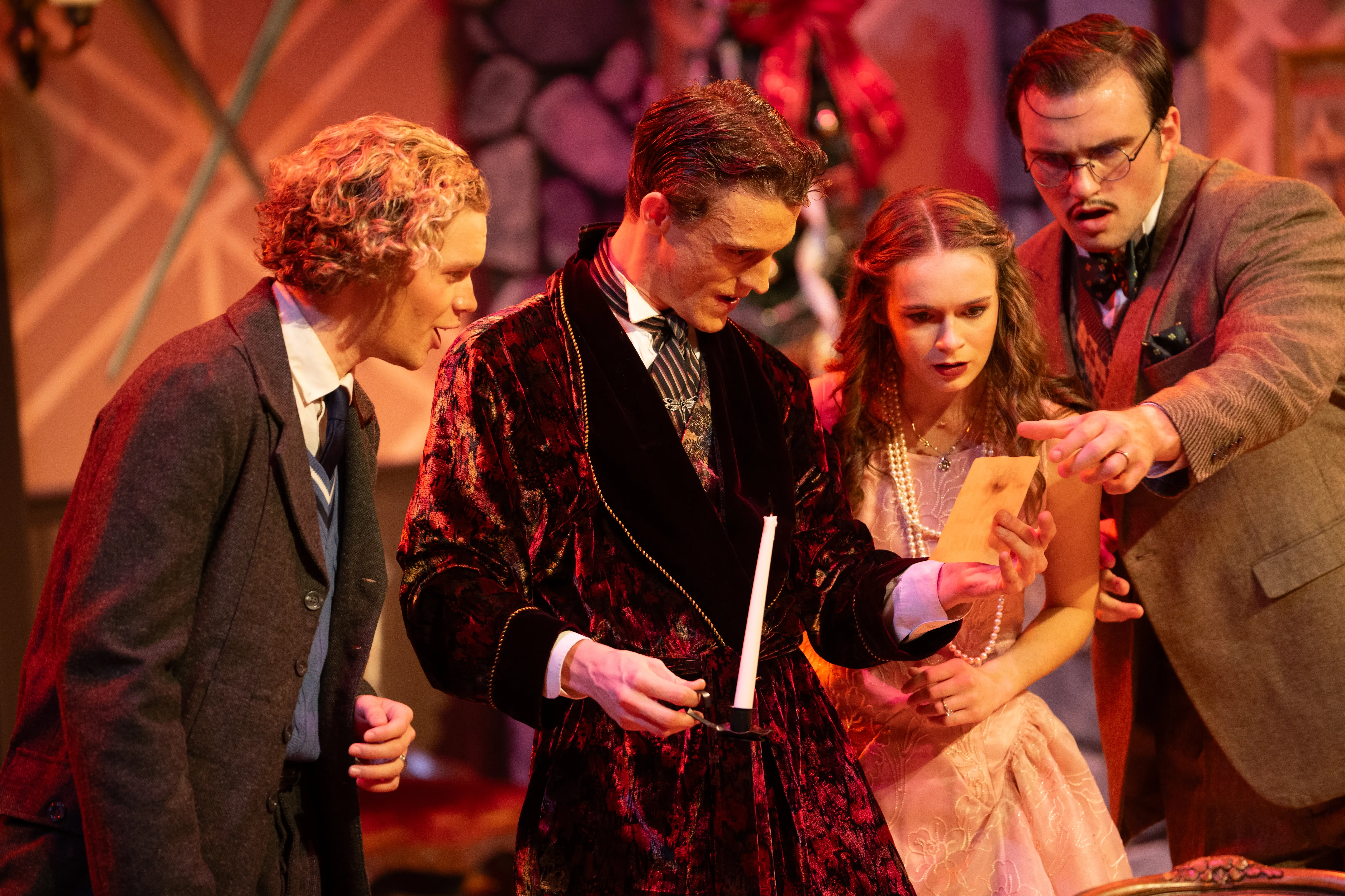 Four actors examine a letter onstage in Belmont’s Black Box Theater, dressed in vintage costumes with intense expressions during a dramatic scene.