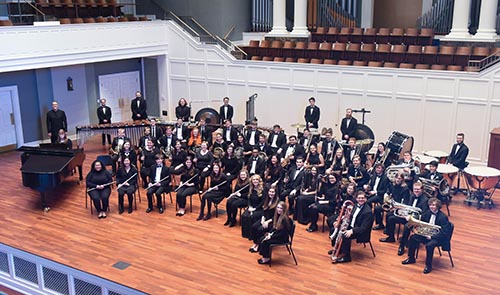 Wind Ensemble posing for picture on the McAfee stage