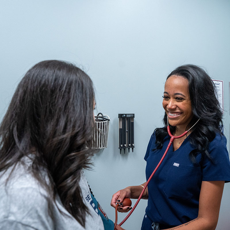 Nurse listening through stethoscope in doctors office