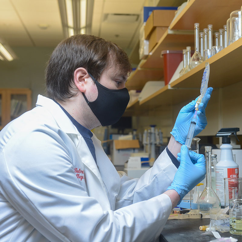 Pharmacy student using syringe to measure medicine