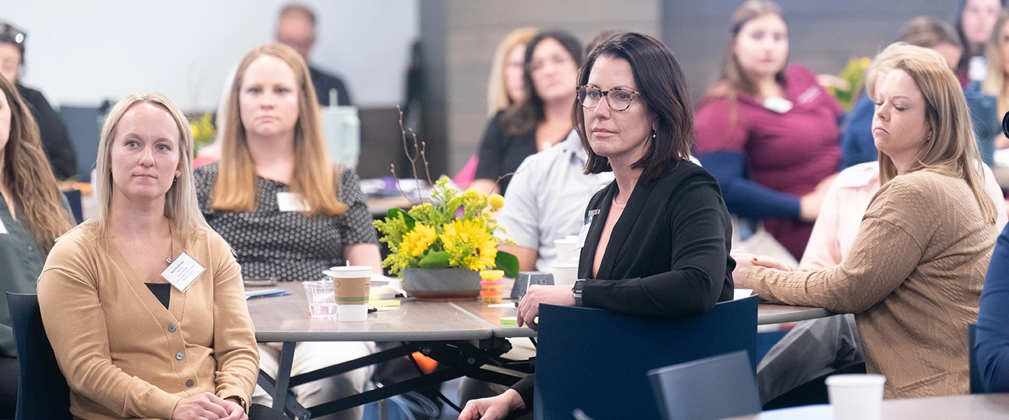 Participants from 2024 CNI Summit seated at tables and listening to a speaker.