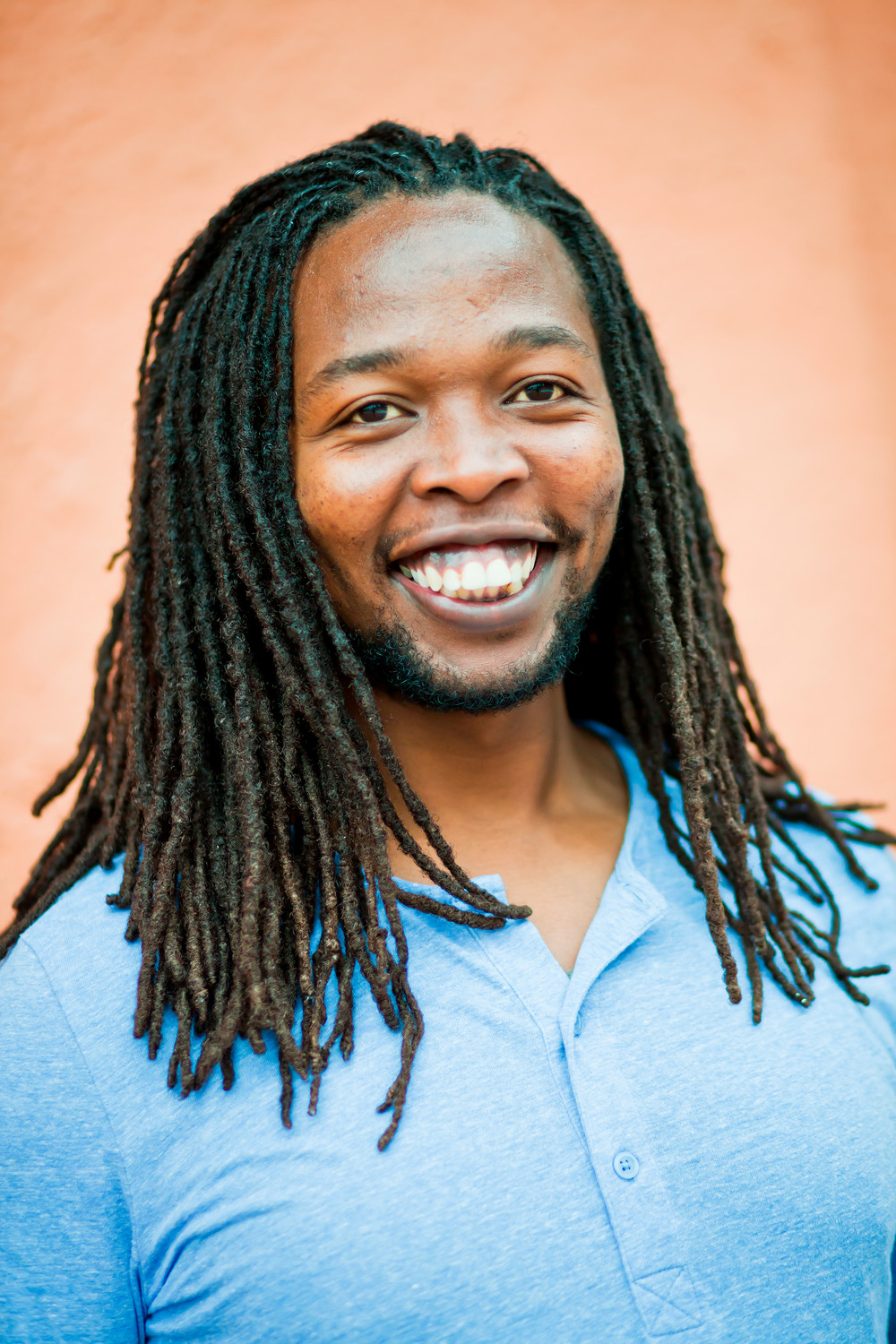 Jay Mbira in front of a brick wall