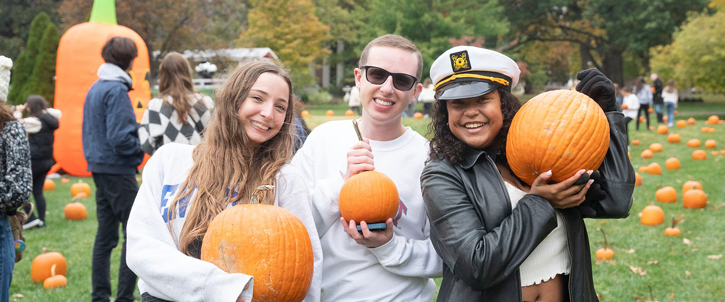 Three students holding pumpkins at Fall Festival