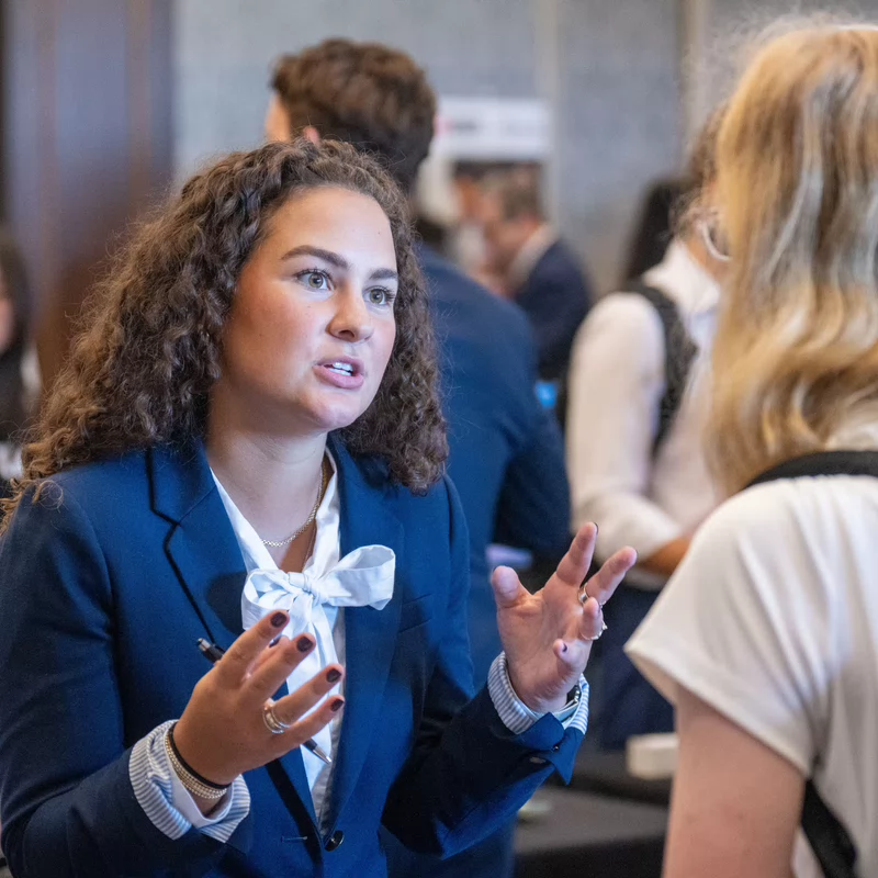 Student conversing with professionals at Business & Tech career expo