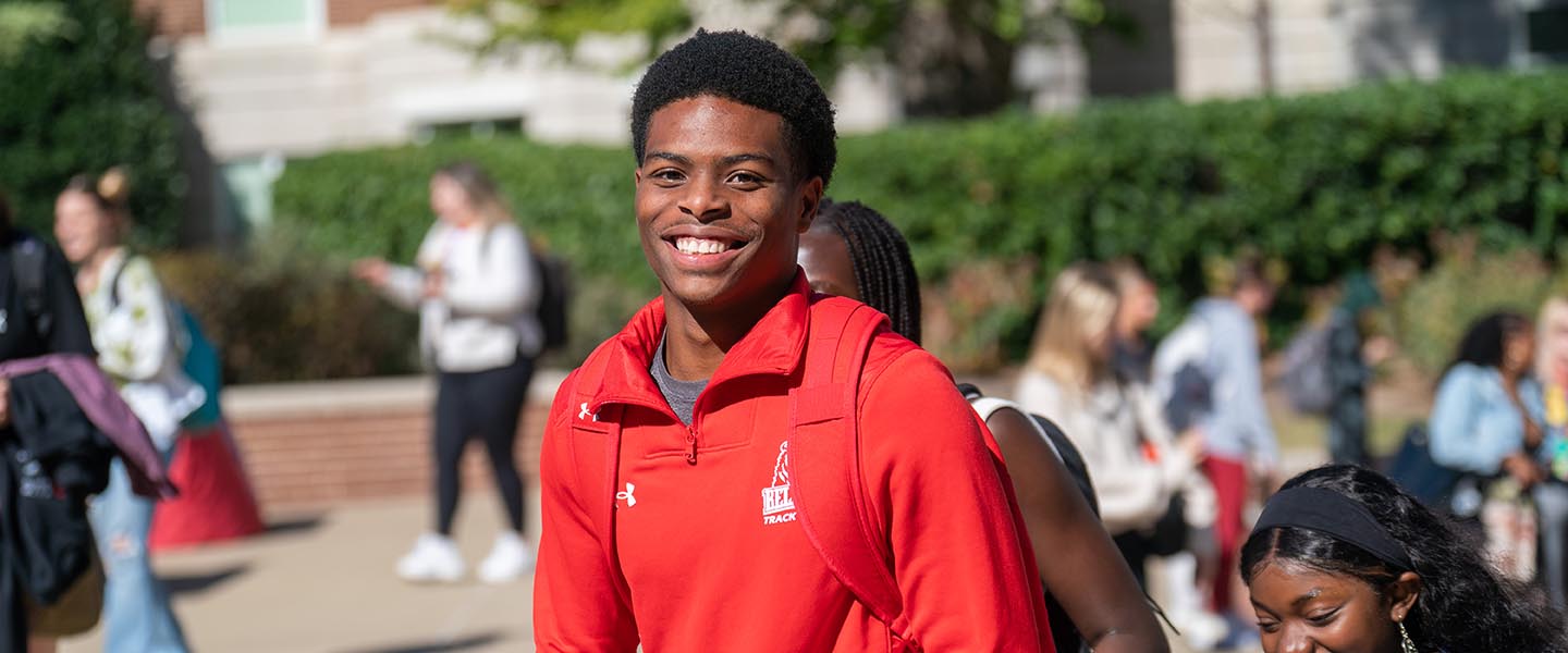 Student smiling at camera while walking around at It Must be Wednesday