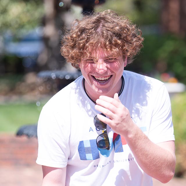 Undergrad student laughing outside on the lawn on the historic side of campus