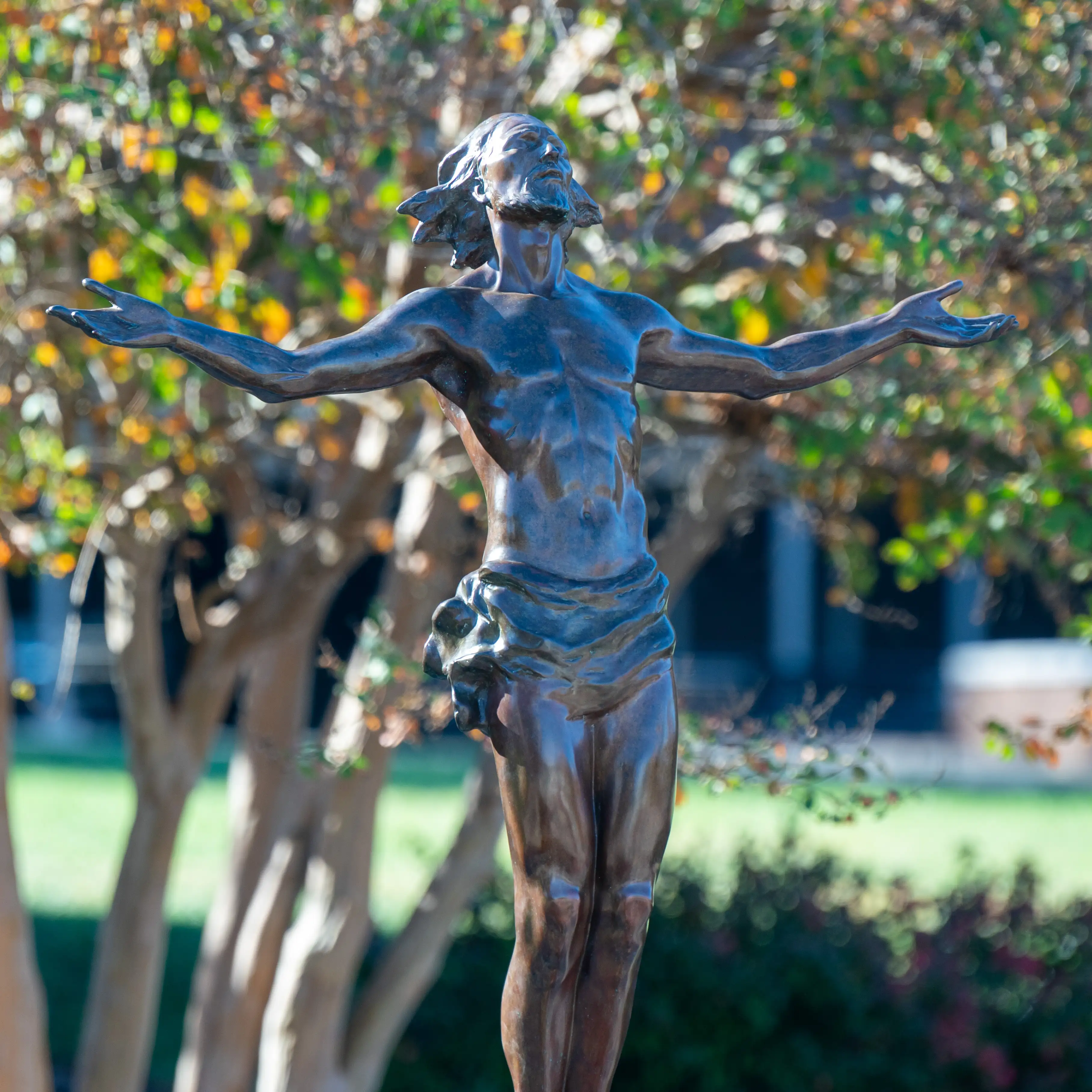 The bronze statue of Christ with outstretched arms stands among trees on Belmont University’s campus, symbolizing the university’s Christ-centered mission.