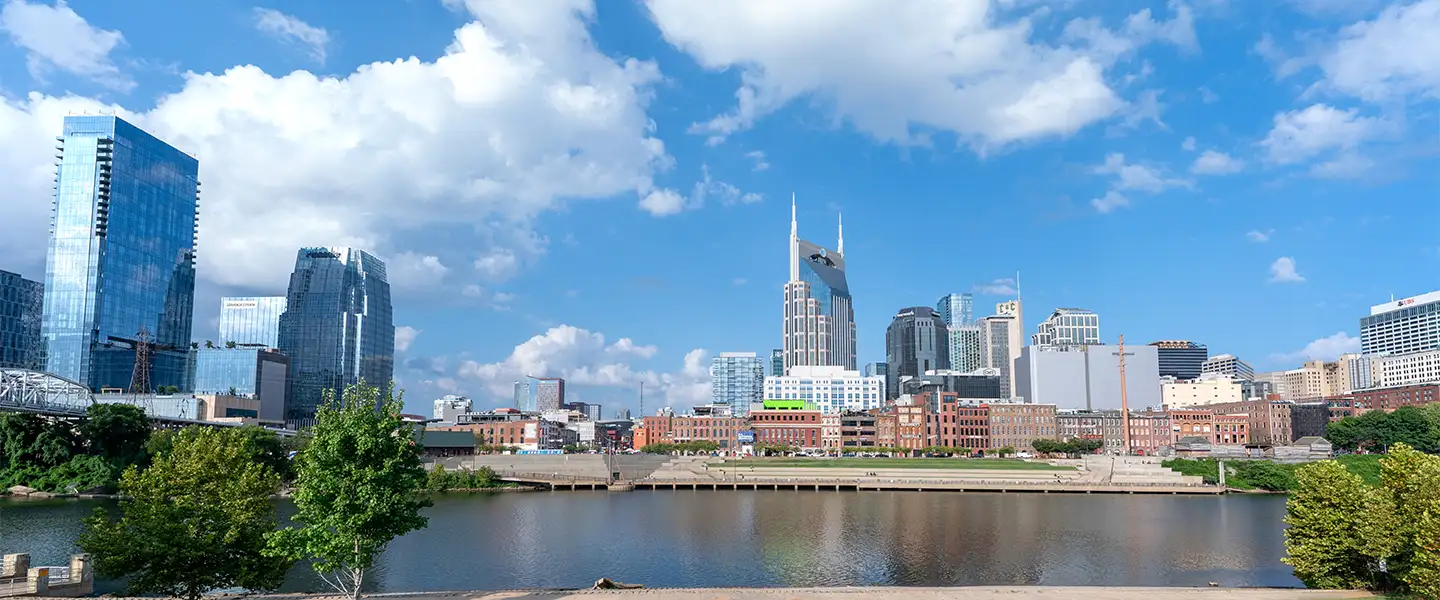 An outdoor photo of the downtown Nashville skyline from across the Cumberland River and facing west on a sunny day
