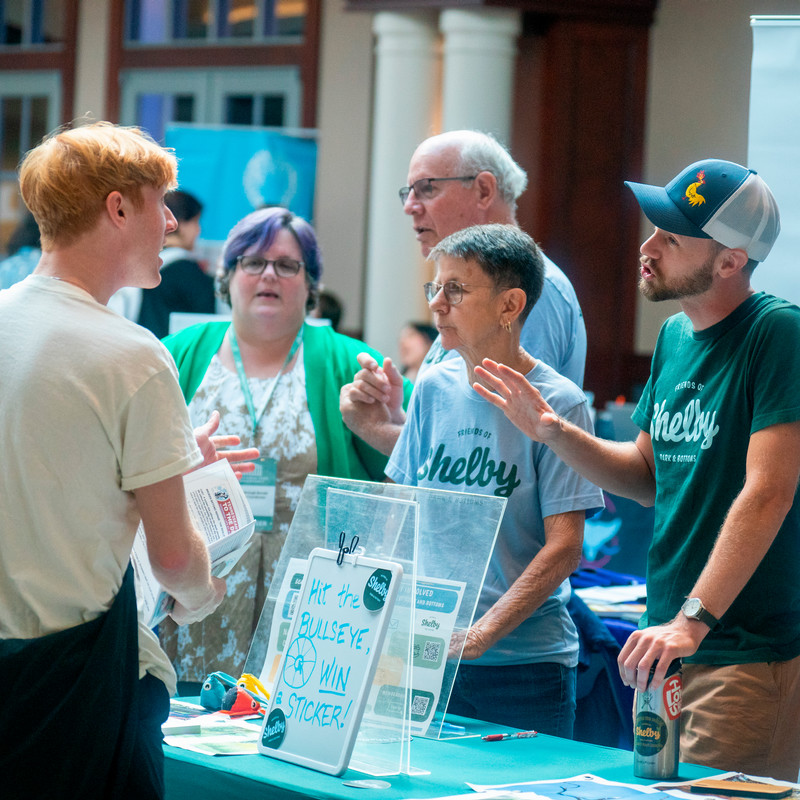 a student talks with representatives from Shelby Parks at a table during the fair