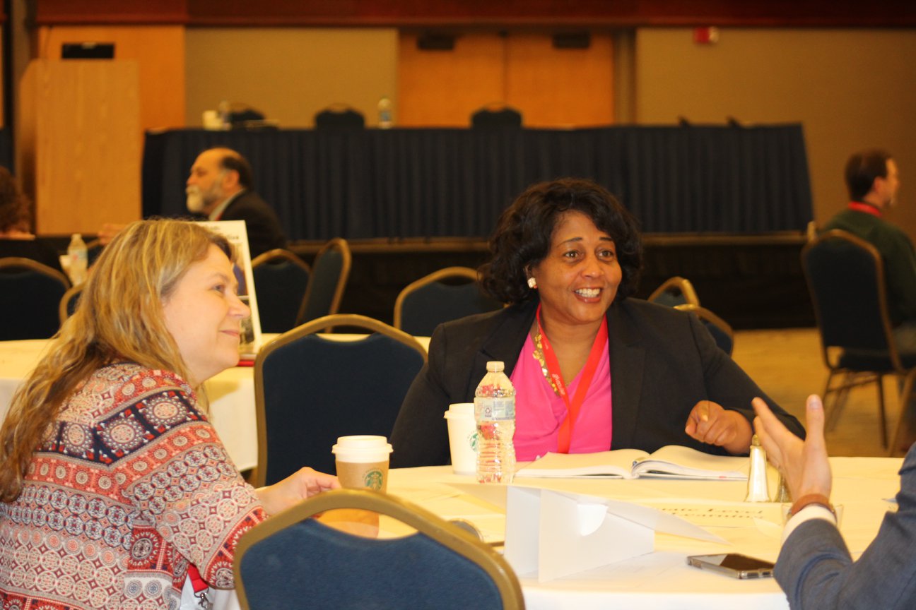 two women engage in conversation at a round table