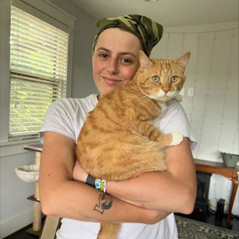 Nora smiles while holding her orange cat