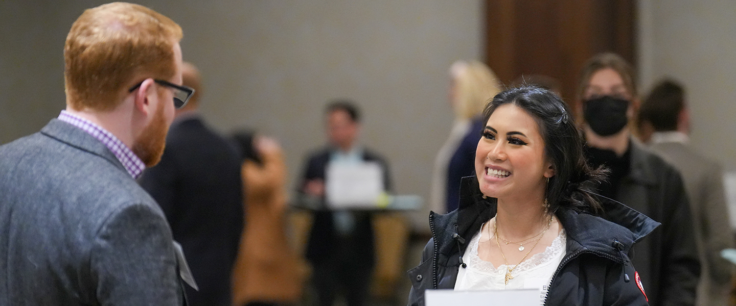 A student talking to a gentlemand during a business networking opportunity.