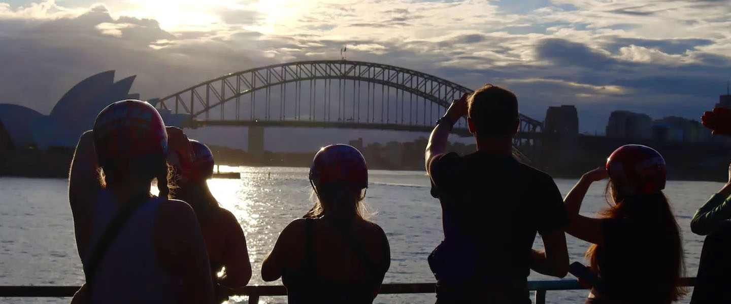 Silhouetted students with the Sydney Harbour Bridge in the background at sunset