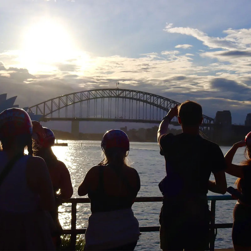 Silhouetted students with the Sydney Harbour Bridge in the background at sunset